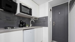 Uma cozinha compacta com micro-ondas, cafeteira e lava-louças.