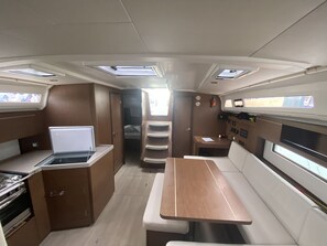 A compact RV interior with a kitchenette, a dining area, and a small bedroom. - Sun-Kissed Sailing Adventure in the Ionian Islands, Lefkada (Lefkada)