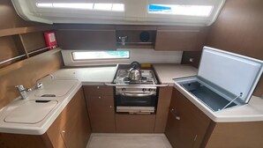 A compact galley with a stove, sink, and a small window. - Sun-Kissed Sailing Adventure in the Ionian Islands, Lefkada (Lefkada)