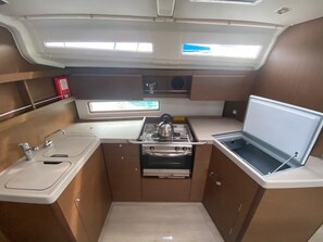 A compact galley with a stove, sink, and a small window. - Sun-Kissed Sailing Adventure in the Ionian Islands, Lefkada (Lefkada)