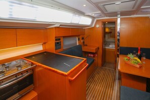 A compact galley with a stove, a small seating area, and a dining table with a fruit basket. - Sun-Kissed Sailing Adventure in Split, Croatia (Kaštel Gomilica)