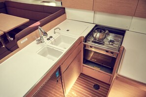 A compact kitchenette with a sink, stove, and storage drawers. - Sun-Kissed Sailing Adventure in Istria, Croatia (Pula)