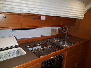 A compact kitchenette with a stove, sink, and storage cabinets. - Sun-Kissed Sailing Adventure in the Ionian Islands, Lefkada (Lefkada)