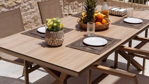 A table set with plates, cutlery, a fruit basket, a glass, and a bottle, with a view of the sea and mountains in the background. - Brikis Villa 1 - With Private Pool (Mylopotamos)