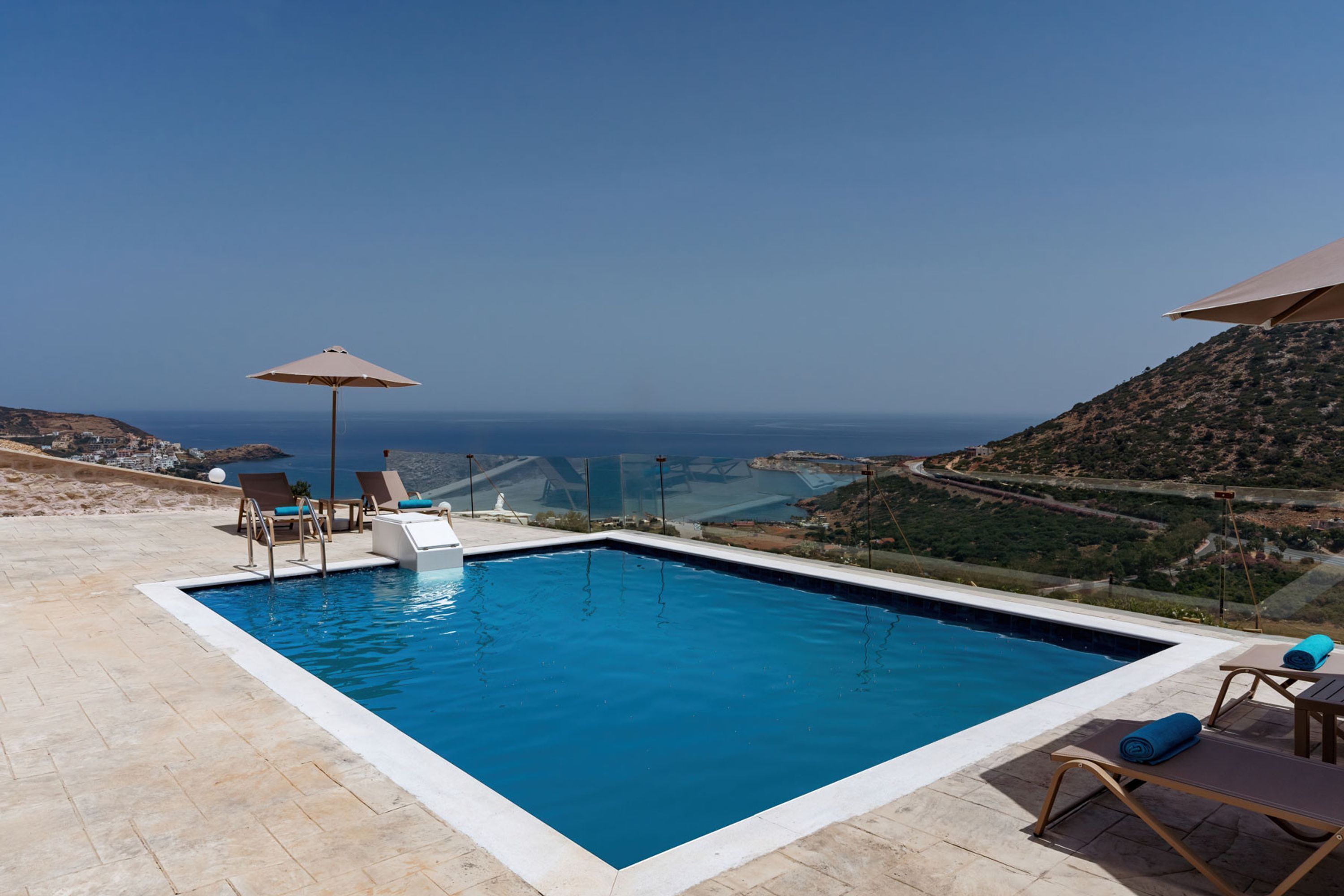 Une piscine rectangulaire offrant une vue dégagée sur l’océan et les collines en arrière-plan.