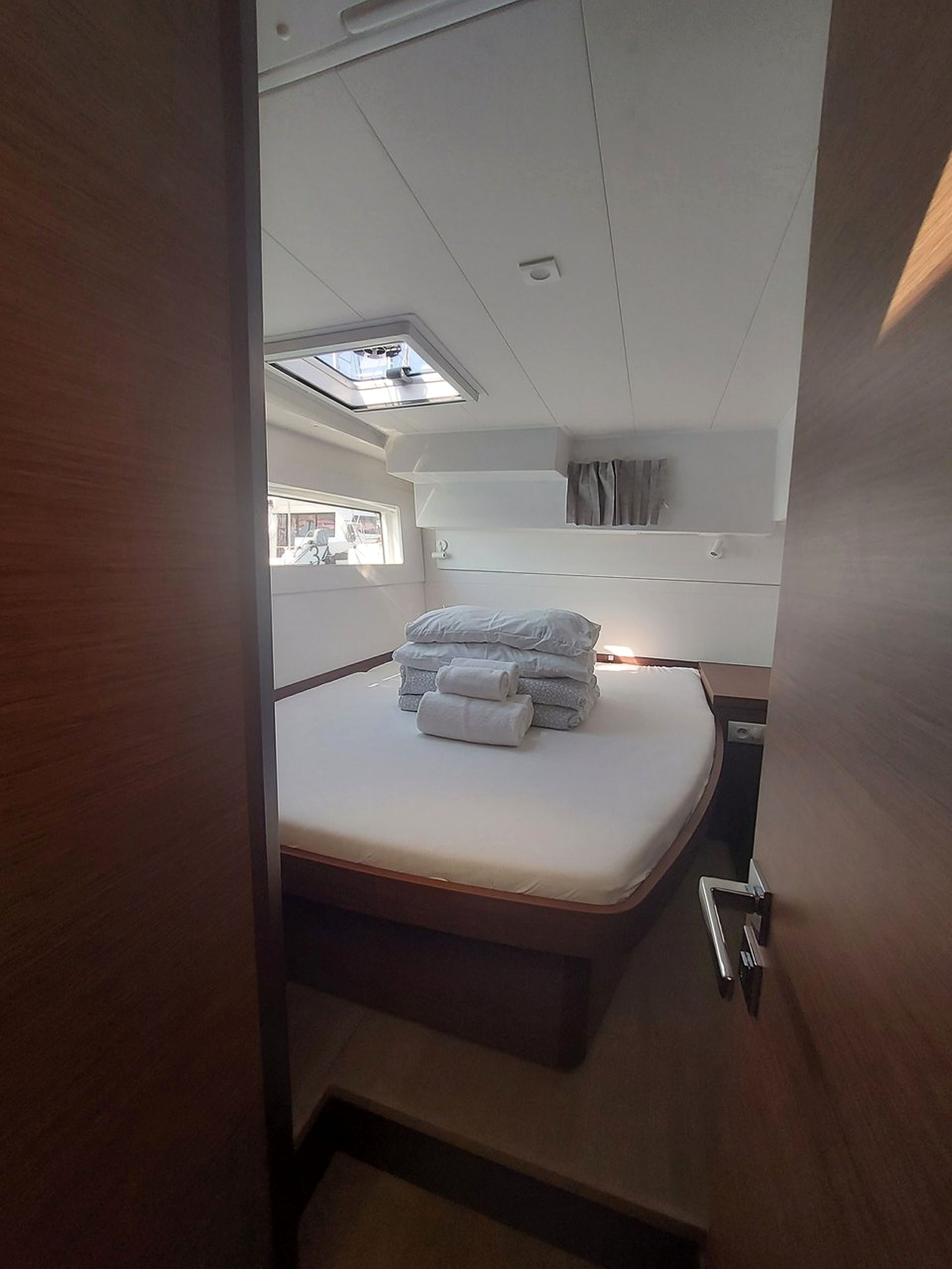 A compact bedroom with a bunk bed, a skylight, and a small window.