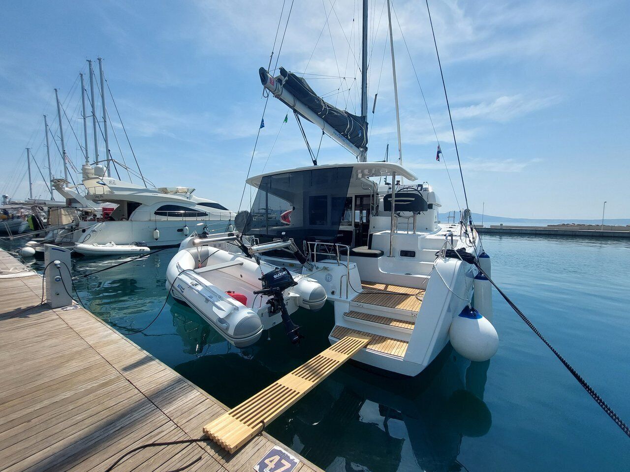 A marina with several boats docked, a wooden deck, and a clear sky.