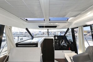The interior of a boat with a steering wheel, control panel, and seating area. - Sibenik Sun-soaked Sailing: A Luxurious Croatian Voyage (Pirovac)