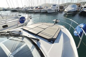 Ein Hafen mit mehreren angestaubten Booten, ein Bootsdeck mit einer gepolsterten Sitzecke und einem wolkenlosen Himmel.