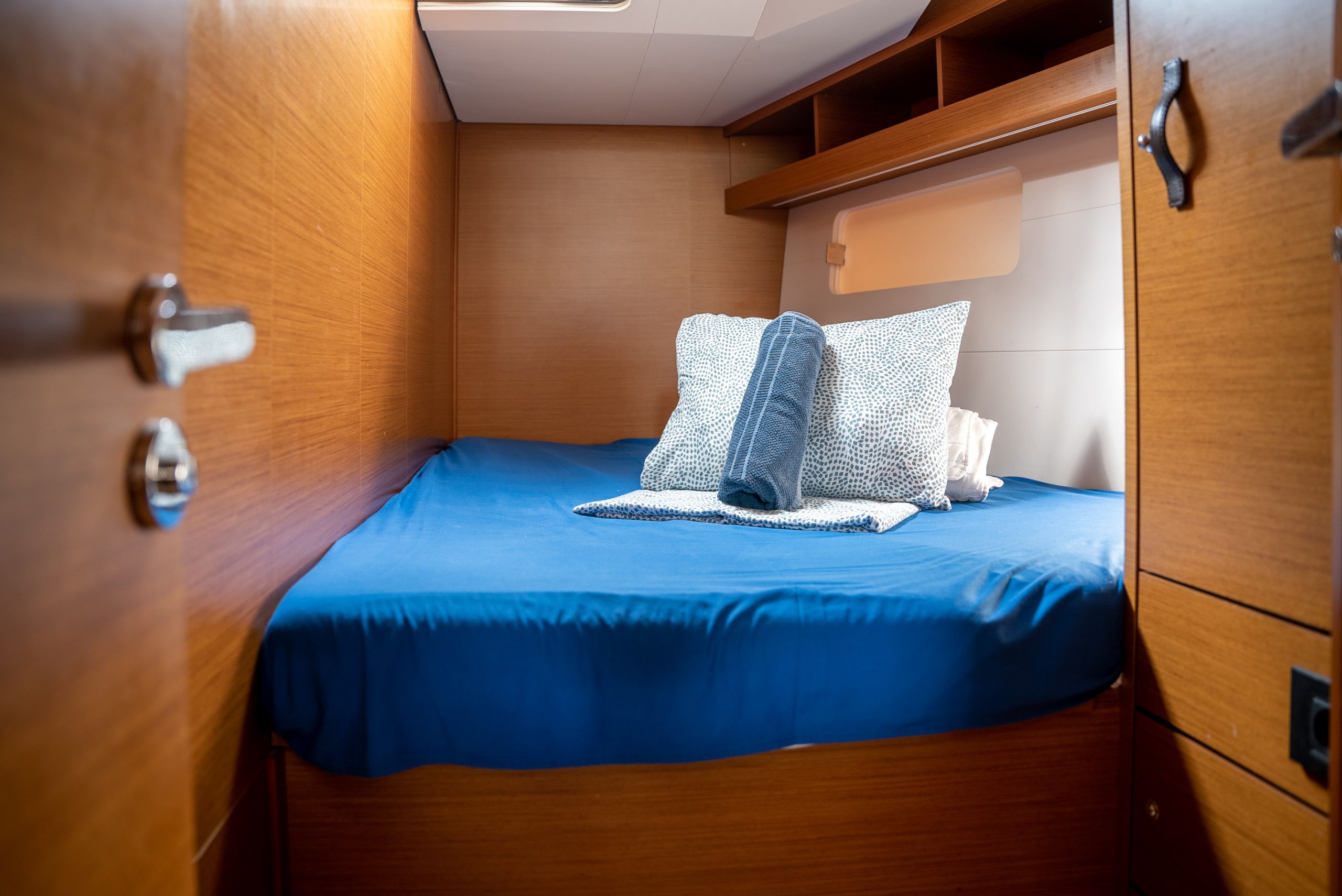 Una cabaña pequeña con una cama individual, paredes de madera y un estante pequeño en el techo.