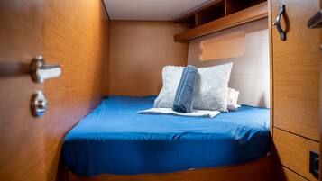 Una cabaña pequeña con una cama individual, paredes de madera y un estante pequeño en el techo.