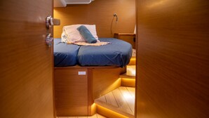Ein gemütlicher, hölzerner Raum mit einem Bett, einem kleinen Nachttisch und einer integrierten Sitzbank.