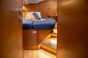 A compact, wooden interior with a bed featuring a blue mattress and a patterned pillow.