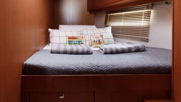 A compact bedroom with a skylight, a bed with pillows, and built-in storage.