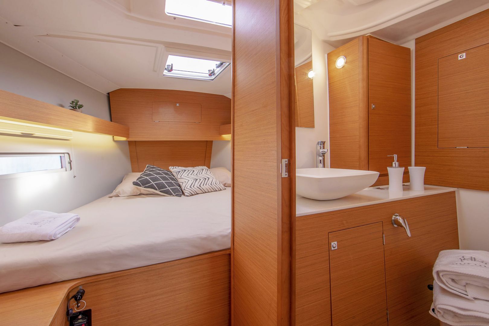 A compact, well-lit cabin with a bunk bed, a vanity with a sink, and a mirror.