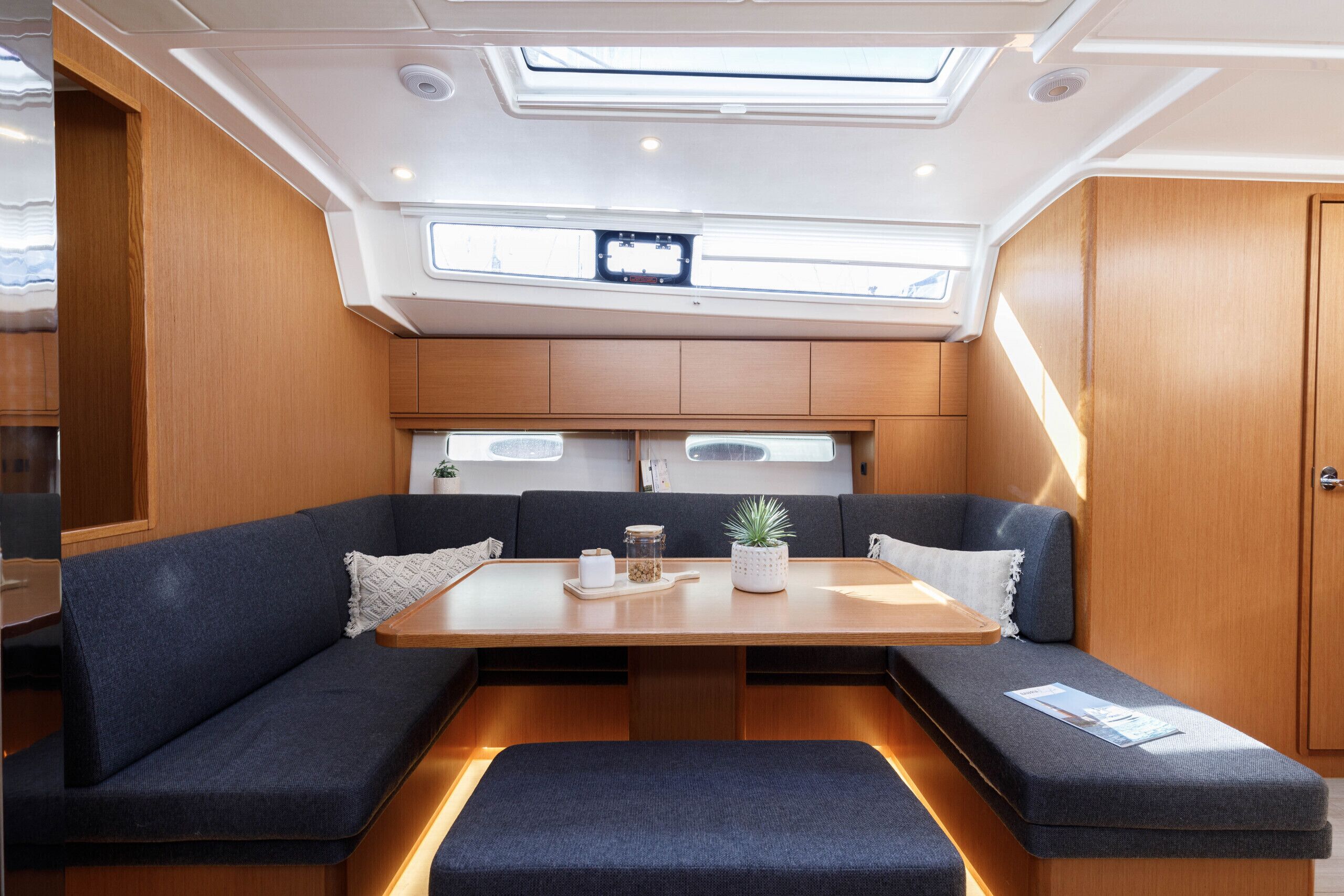 A compact, well-lit interior with a central table, cushioned seating, and a skylight above.