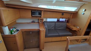 A compact RV interior with a kitchenette, a cushioned seating area, and a small refrigerator. - Caribbean Sun-Kissed Sailing: A Luxurious Beach Experience from Martinica, Le Marin (Le Marin)
