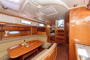 A compact, well-lit interior with a wooden table, cushioned seating, and a small window. - Sun-kissed Sailing Adventure in Split-Dalmatia, Croatia (Trogir)