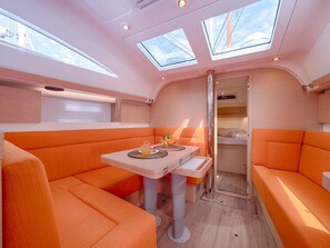 Ein kompakter, moderner Innenraum mit orangenen Sitzgelegenheiten, einem kleinen Tisch mit einem Getränk und Dachfenstern.