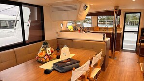 L’intérieur d’un bateau, avec un coin repas, une cuisine et une vue sur l’extérieur.