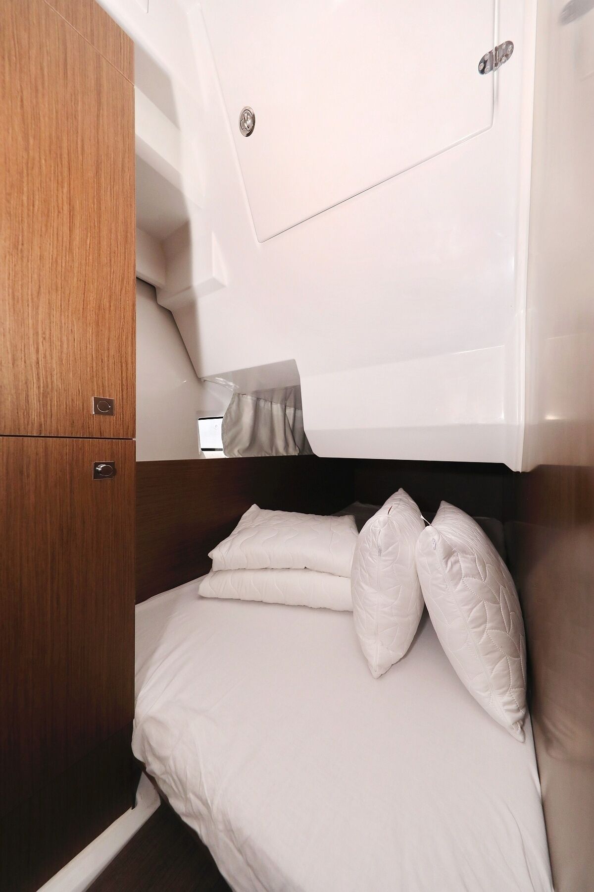 A compact, well-lit cabin with a bed, a small wardrobe, and a window.