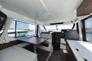 A boat interior with a dining area, seating, and a steering wheel. - Sun-Kissed Sailing Adventure in Zadar, Croatia (Biograd na moru)