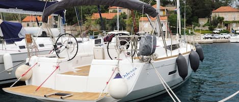Un veler amarrat en una marina amb coberta coberta, un timó i una cabina.