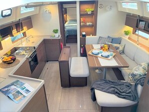 A compact, well-lit interior with a kitchenette, dining area, and seating space. - Sun-Kissed Sailing Adventure in Split, Croatia (Split)