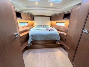 A compact, well-lit bedroom with a bed, bedside tables, and built-in storage.
