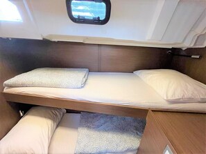 A compact bunk bed with a window above, a wooden headboard, and a small overhead compartment. - Sun-Kissed Sailing Adventure in Split, Croatia (Split)