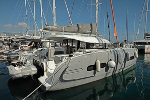 Eine Yacht liegt in einer Marina festgemacht, mit mehreren Masten, einer überdachten Sitzgelegenheit und diverser Navigationstechnik.