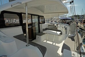 Ein Bootsdeck mit Sitzgelegenheiten, einer Steuerung und Blick auf den Hafen.