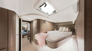 Una camera da letto moderna con un lucernario, un letto con coperta rosa, un comodino e un armadio.