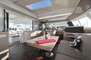 A yacht interior with a dining area, kitchen, and a large window. - Sun-kissed Sailing Adventure in Split-Dalmatia, Croatia (Seget Donji)