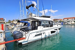 Ein weißes Motorboot liegt in einer Marina ab, mit einem überdachten Sitzbereich und einem Yamaha Außenbordmotor.