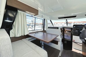 Un intérieur de camping-car compact comprenant un coin repas, un volant et une vue sur le port de plaisance.