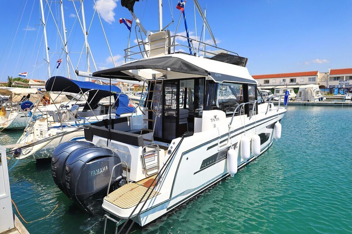 Un bateau à moteur blanc était amarré dans une marina. Il était équipé d’un moteur hors-bord Yamaha, d’un espace de repos couvert et d’une cabine portant le nom « MERRY FISH ».
