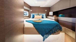 Ein modernes Schlafzimmer mit Dachfenster, einem Bett mit blau-beigen Bettwaren und einem Nachttisch mit Dekoration.
