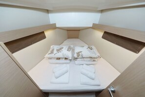 Ein kleiner, gut beleuchteter Raum mit einem Bett, Kissen und einer kleinen Ablage.