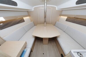 Un interior modern i compacte, amb una taula central, seients amb coixins i un pal vertical.