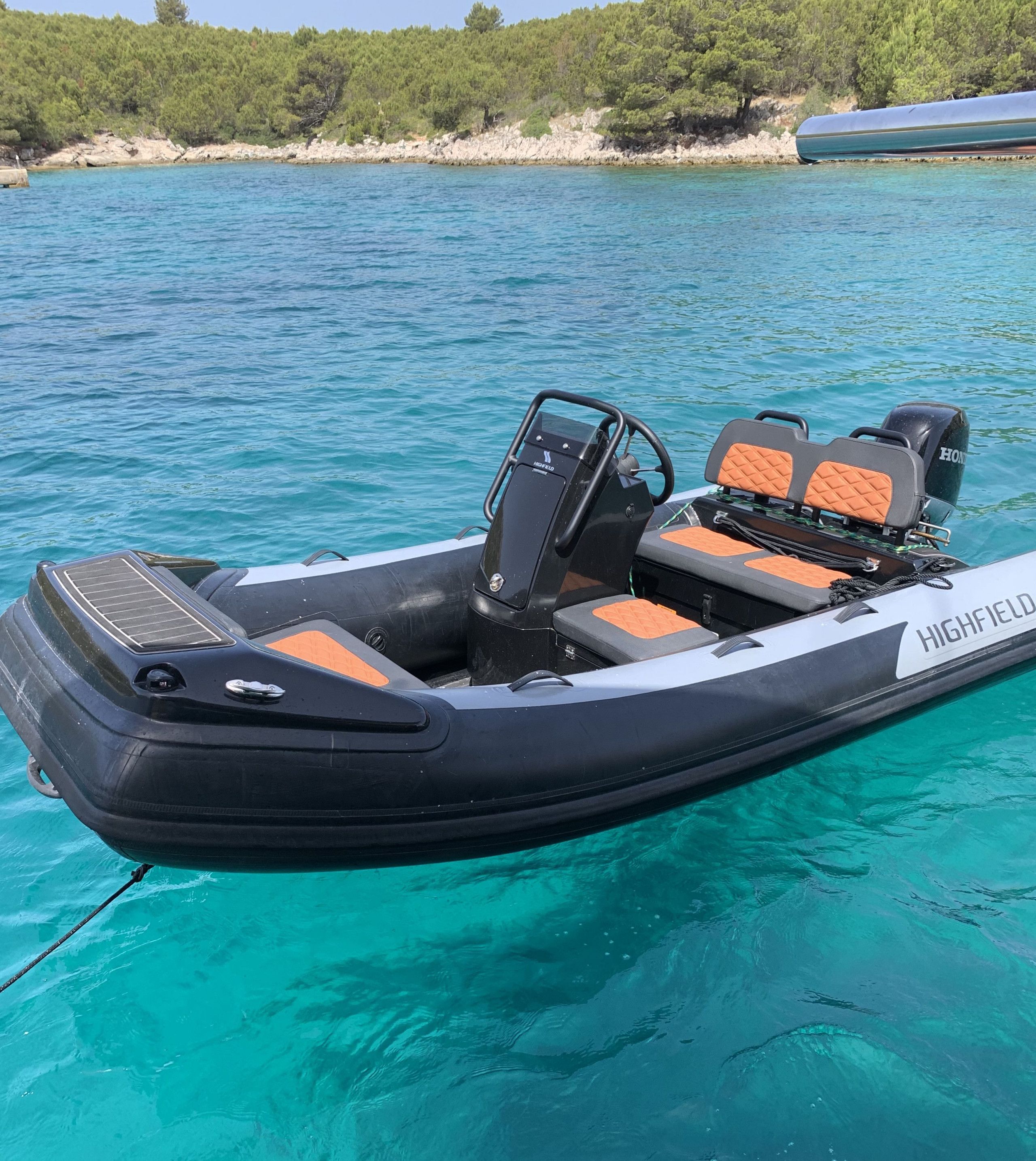 Una piccola barca gonfiabile con posti a sedere, un timone e un motore.
