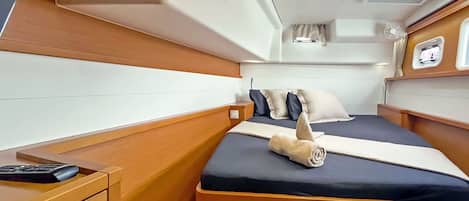Una cabaña pequeña con una cama, mesita de noche y un ventanal.