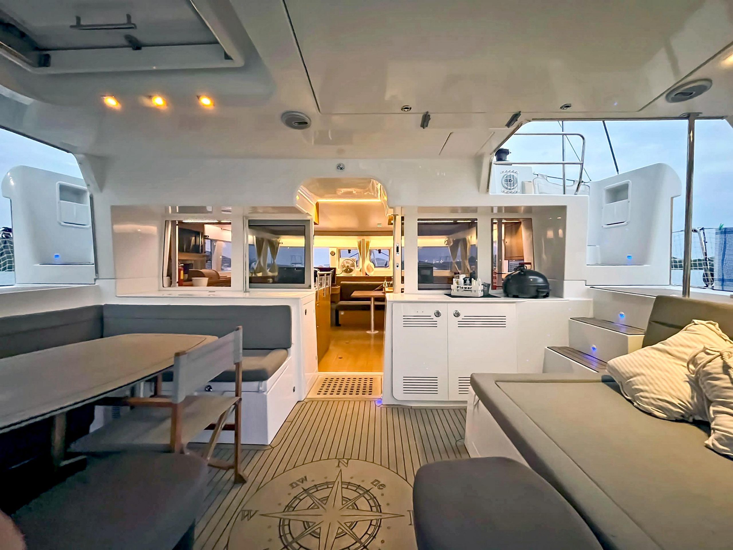 A yacht's interior with a dining area, a kitchen, and a seating area with a view.