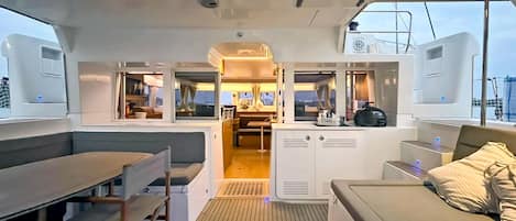 A yacht's interior with a dining area, a kitchen, and a seating area with a view.