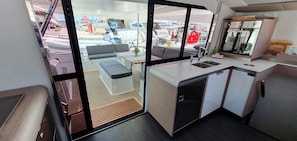 A compact kitchen with a sink, a small refrigerator, and a window overlooking a marina. - Sun-kissed Sailing Adventure in Split-Dalmatia, Croatia (Seget Donji)