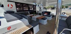 A yacht interior with seating, tables, and a logo. - Sun-kissed Sailing Adventure in Split-Dalmatia, Croatia (Seget Donji)