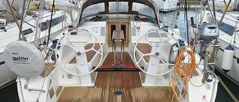 A boat deck with a steering wheel, a winch, and a covered area.