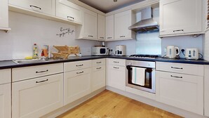 Une cuisine moderne avec des armoires blanches, un four à micro-ondes, une cuisinière et un évier.