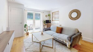 Un salon comprenant un canapé, une table basse, un téléviseur et une porte donnant sur un balcon.