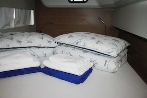 Ein Bett mit weißer und blauer Bettwäsche, ein Fenster mit Vorhängen und ein hölzernes Kopfende.